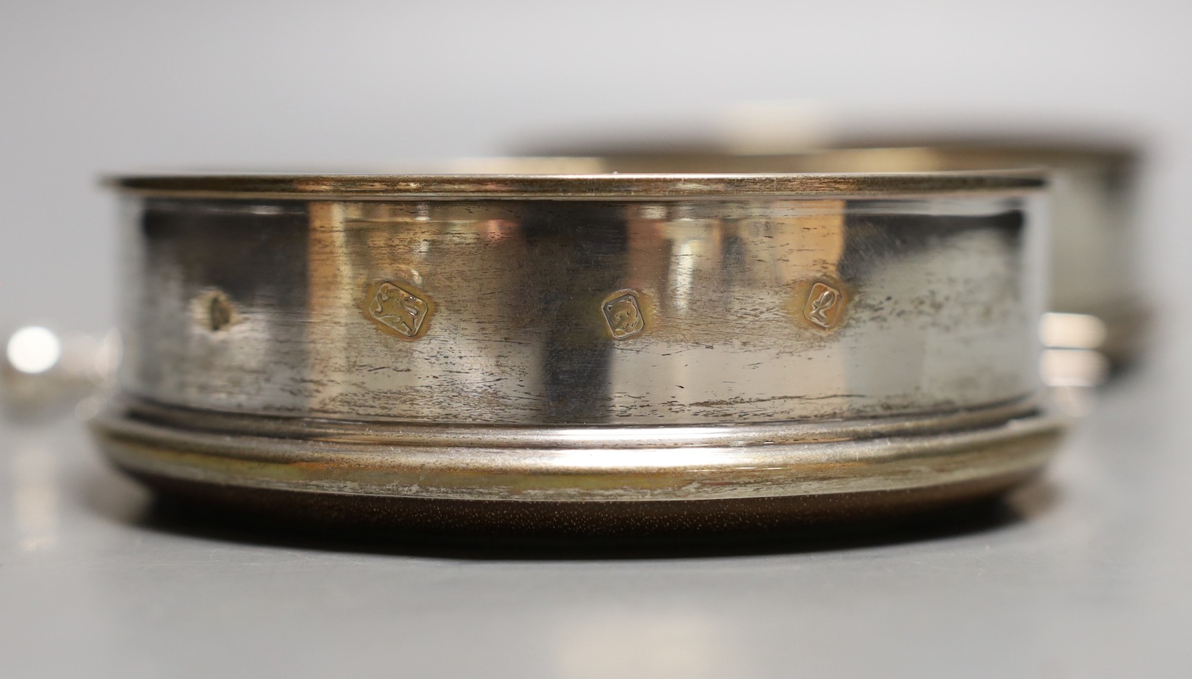 A modern pair of silver mounted wine coasters, London, 1985/6, diameter 12.5cm and a white metal and mother of pearl toasting fork.